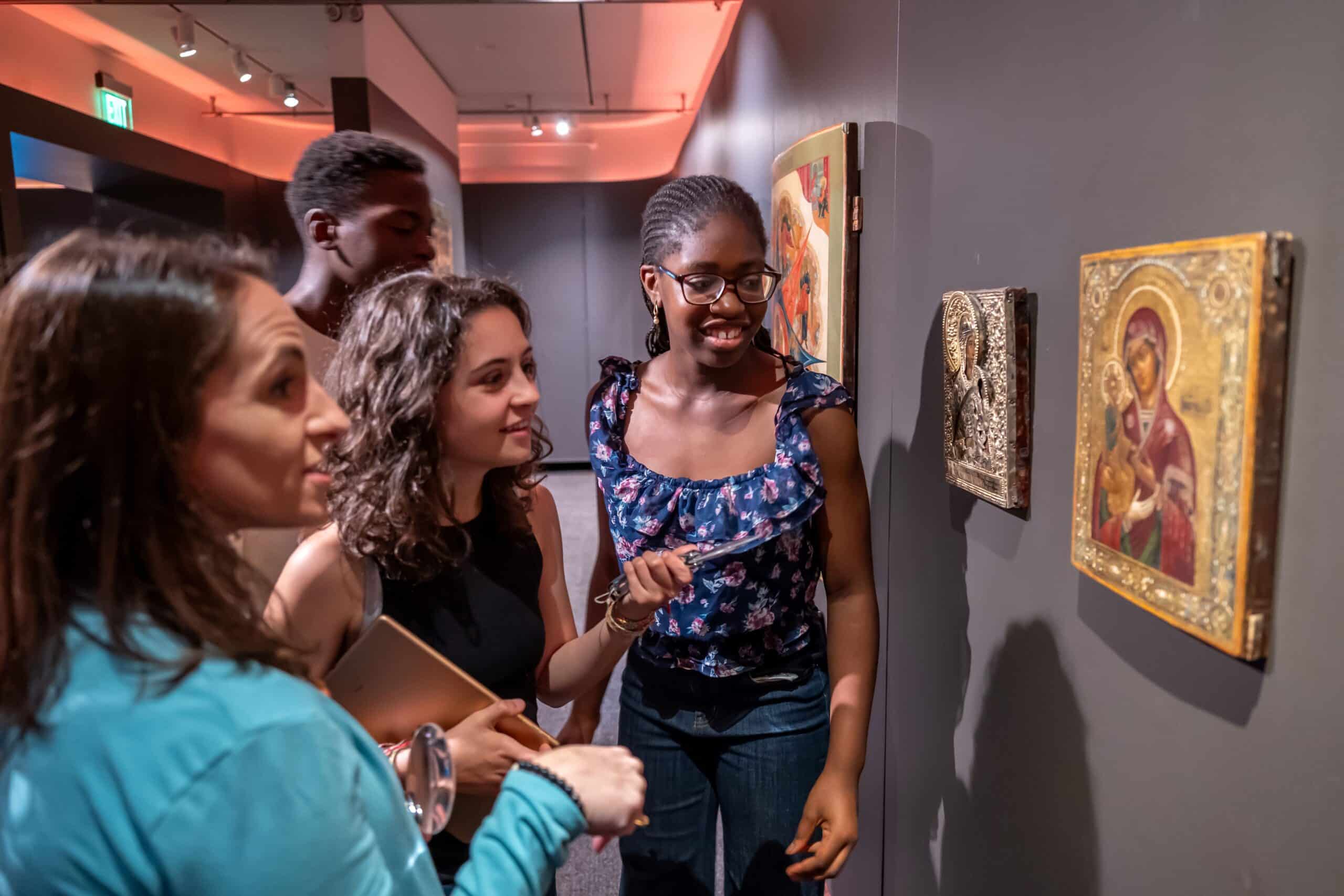 A woman and three teenagers looking at an icon on the wall