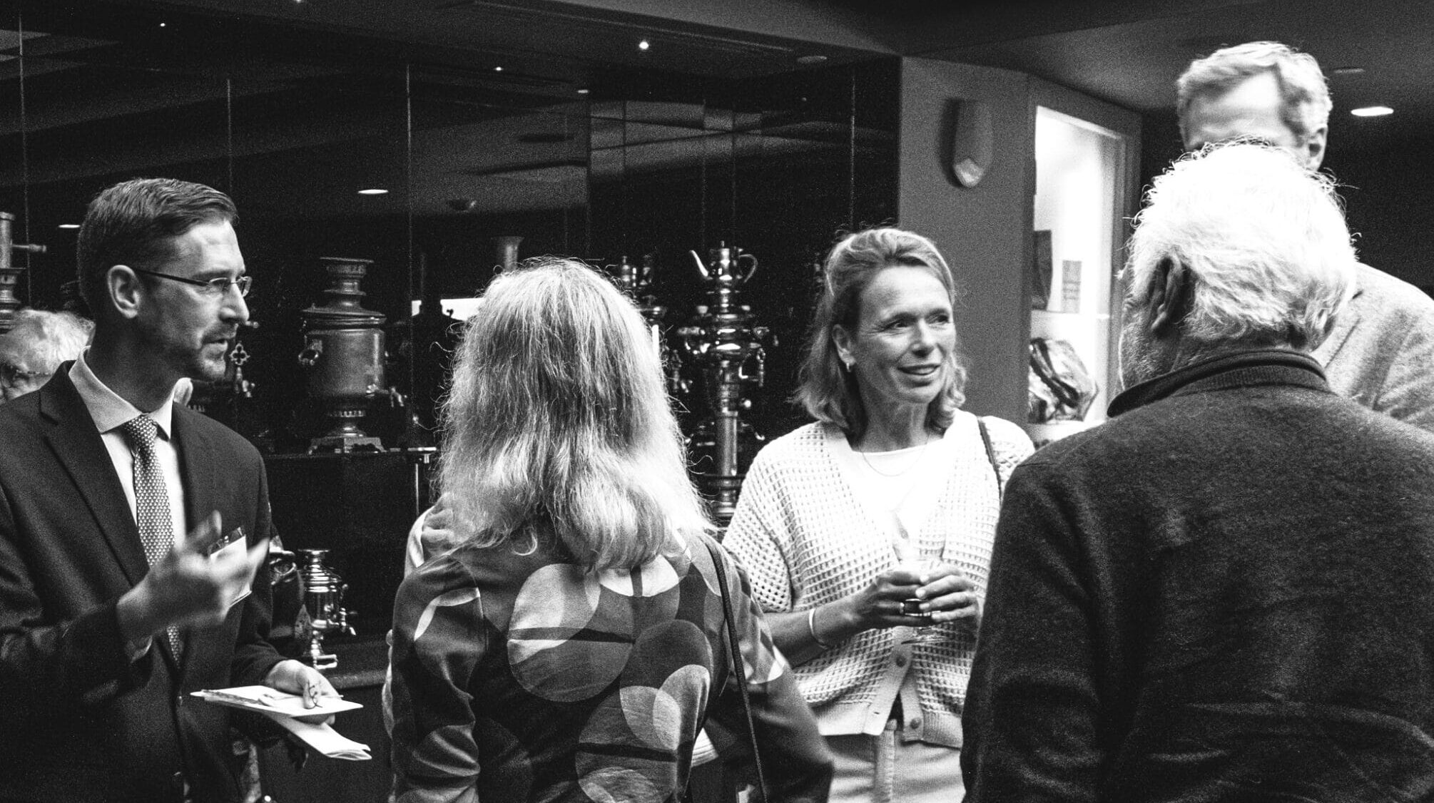 A black and white image with a group of people talking.