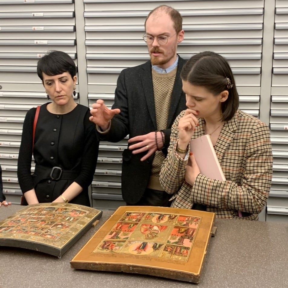Three people studying two icon paintings