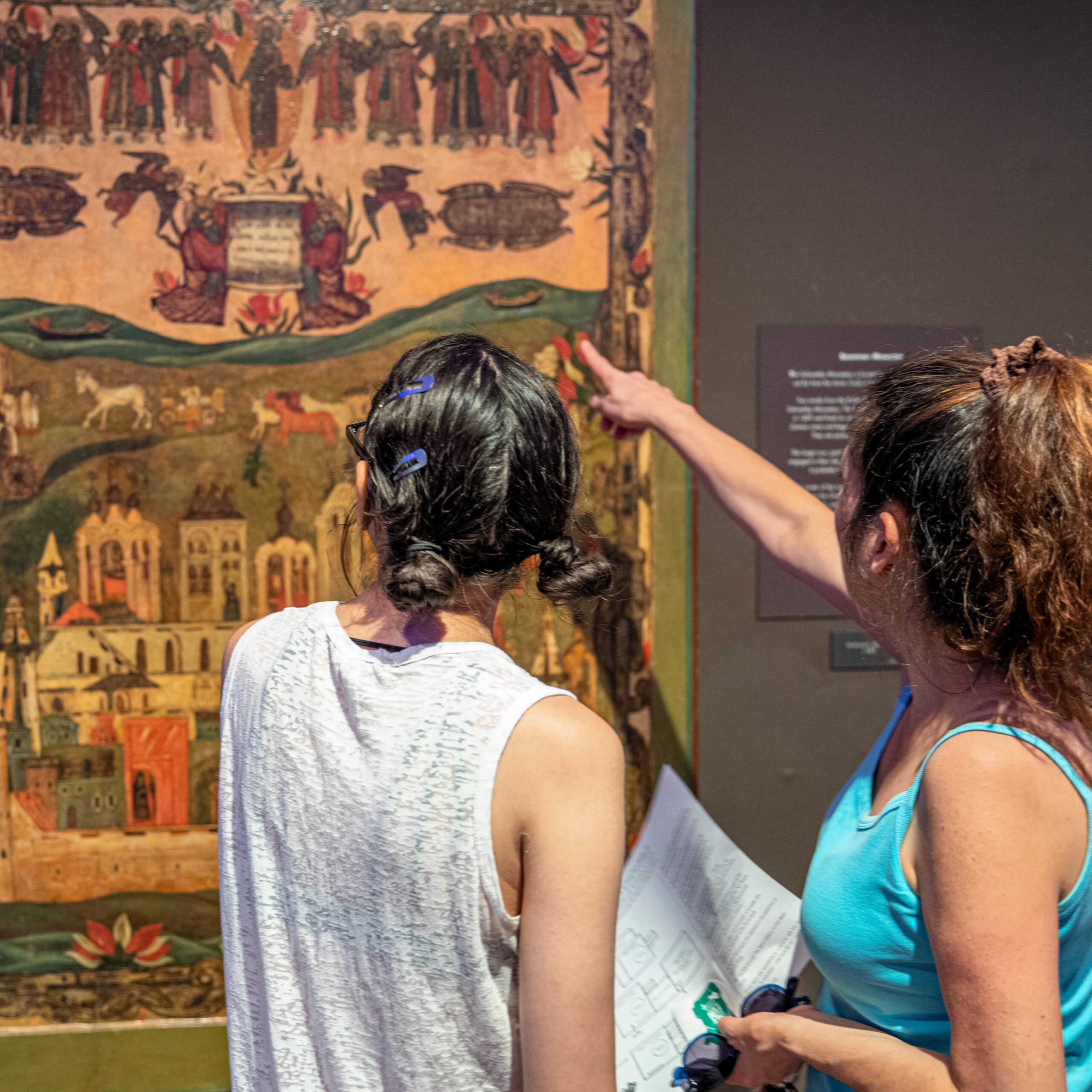 Three people studying two icon paintings