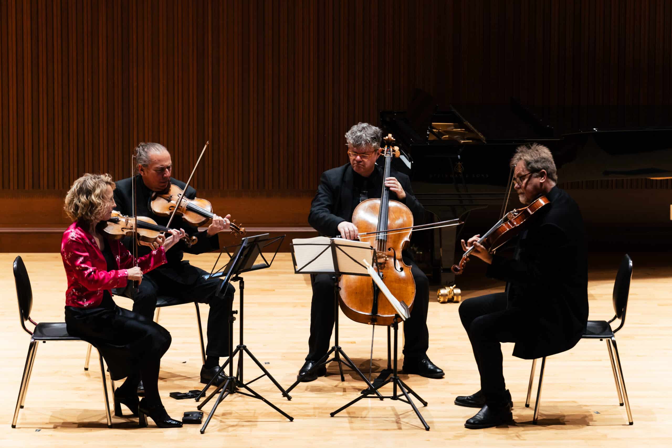 Four musicians facing each other in a circle playing instruments
